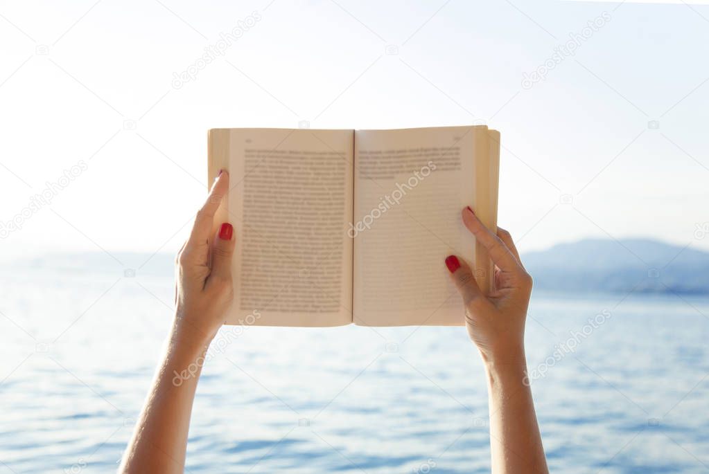 Woman hands holding book on beach