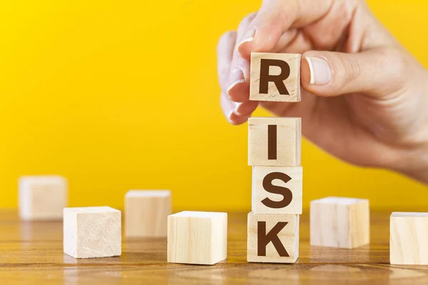 Woman hand arranging wooden cubes with word "risk" — ストック写真