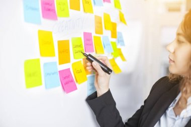 Yaratıcı kadın fikir paylaşmak için post-it notları kullanın