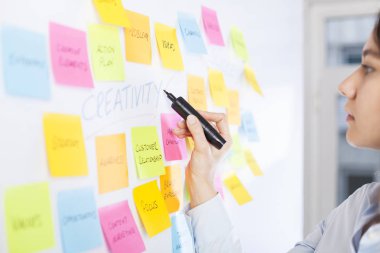 Yaratıcı kadın fikir paylaşmak için post-it notları kullanın