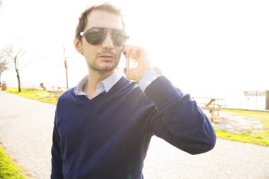 Genç adam parkta telefonla konuşuyor.