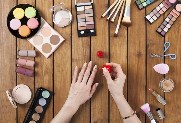 Makeup products with woman doing nail polish — Stock Photo, Image