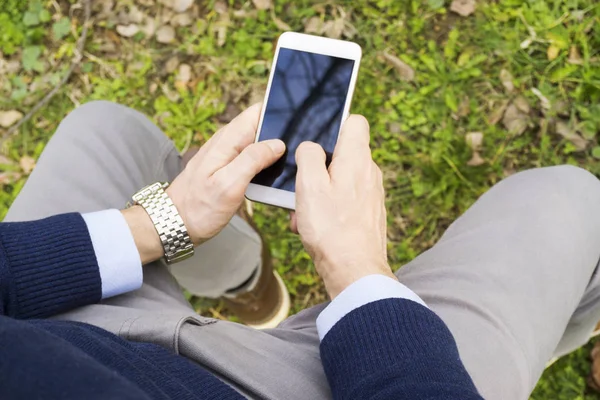 公園での若者のテキストメッセージ彼のスマートフォンで — ストック写真