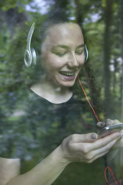 Mujer joven escuchando música mirando a través del windo —  Fotos de Stock