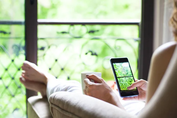 Woman using her smart phone sitting on sof — 스톡 사진