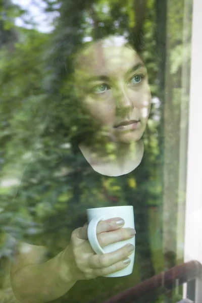 Mujer joven mirando por la ventana vista a través de vidrio —  Fotos de Stock