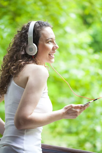 Mujer joven escuchando música desde un teléfono inteligente — Foto de Stock