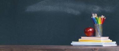 Okul öğretmeni des üzerinde defter üzerinde kalem tepsisi ve bir elma