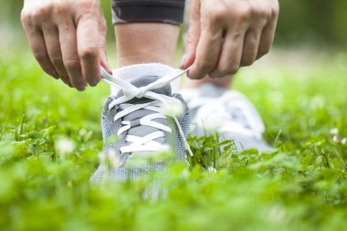 Doğa yolunda ayakkabı bağcıklarını bağlayan kadın koşucu