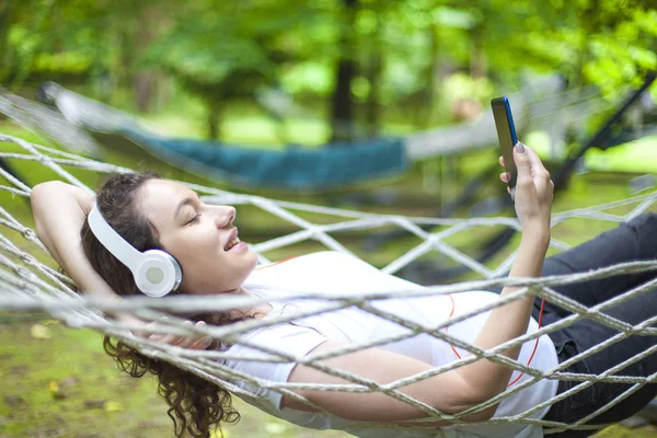 Молодая женщина на гамаке слушает музыку — стоковое фото