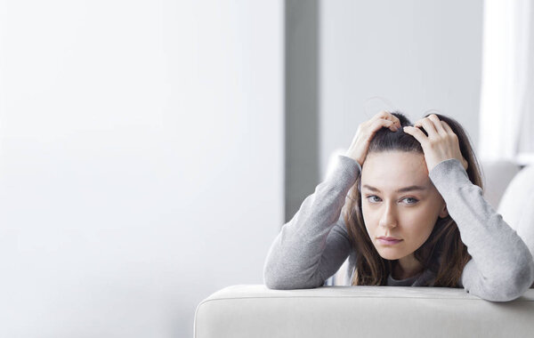 Depressed young woman on sofa at hom