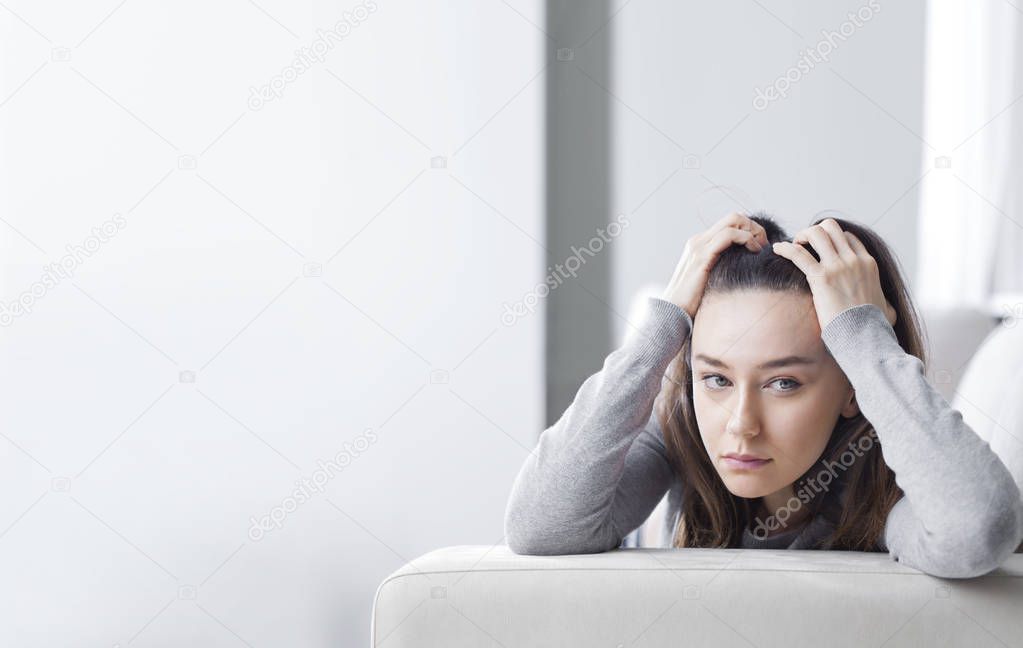 Depressed young woman on sofa at hom