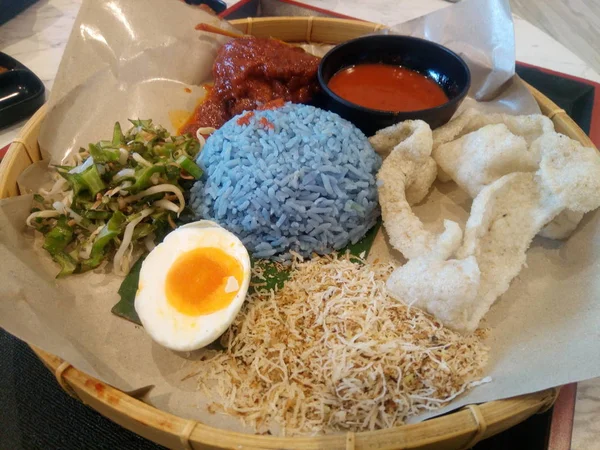 ナシゴレン Kerabu はクランタン料理 ウラム米 干し魚 フライド チキン クラッカー ピクルス他のサラダと ブルー色ご飯を食べるタイプです — ストック写真