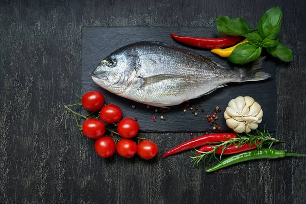 新鮮なシイラ魚スレート チェリー トマト ニンニク ローズマリー コショウ 唐辛子とまな板です トップ ビュー領域にコピーします 黒の背景 — ストック写真