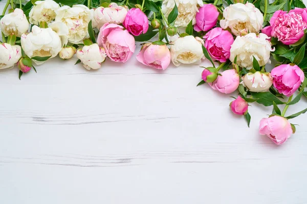 White and pink peonies bouquet on white wooden background. Holiday background, copy space, top view. Mothers Day, Valentines Day, Birthday concept.