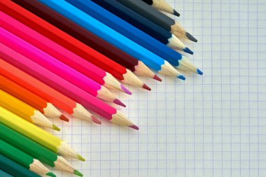 Renkli kalemler üstünde işaretli bir defter. Yakın çekim. Renkli kalemler kağıda bir kafeste. Üstten görünüm