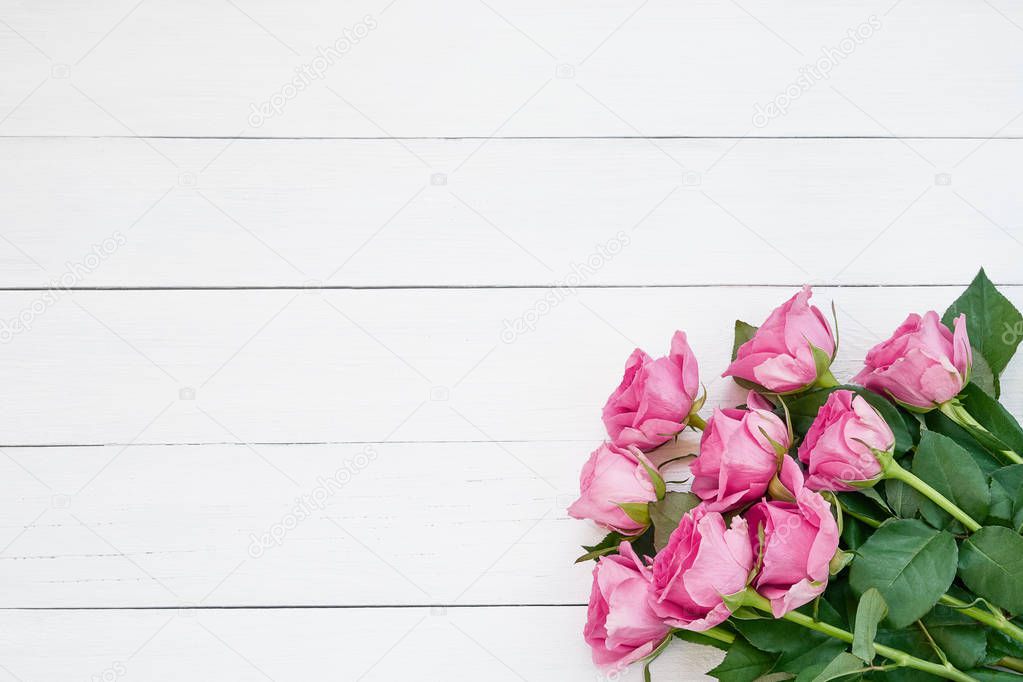 Bouquet of pink roses on white wooden background. Top view, copy space. Greeting card