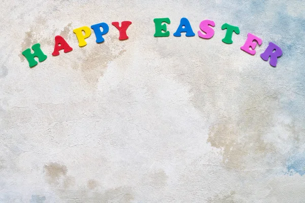 Easter background. Colorful letters forming words HAPPY EASTER on watercolor background. Copy space for your text. Flat lay of Easter celebration concept.