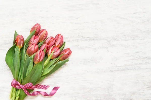 Pink tulips bouquet decorated with ribbon on white background. Copy space, top view — Stock Photo, Image