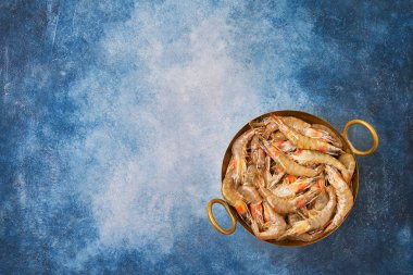 Mavi arka plan üzerinde vintage bir tabak üzerinde çiğ taze karides. Kopya s