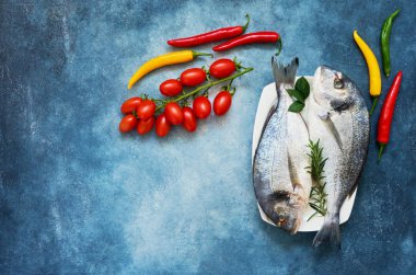 Ham çipura balık sebze üzerinde mavi arka plan ile. Üstten Görünüm,