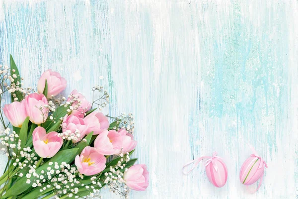 Osterhintergrund. Rosa Tulpen und Ostereier auf blauem Hintergrund — Stockfoto