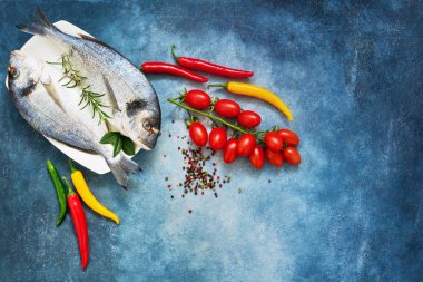 Ham çipura balık sebze üzerinde mavi arka plan ile. Üstten Görünüm,