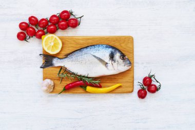 Ahşap kesme tahtası üzerinde baharatlar ile taze dorada balık. Sağlıklı f