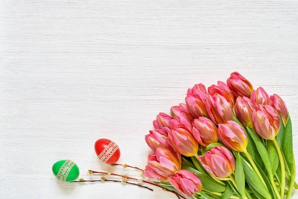 Easter background. Easter eggs and pink tulips on white backgrou
