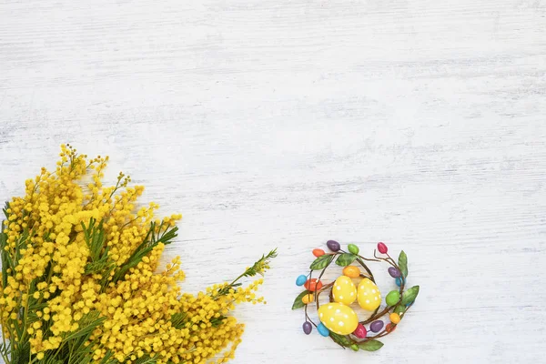 Easter background. Easter decoration and mimosa bouquet on white