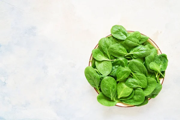 Fresh spinach leaves on white plate. Healthy vegan food. Top vie — Stock Photo, Image