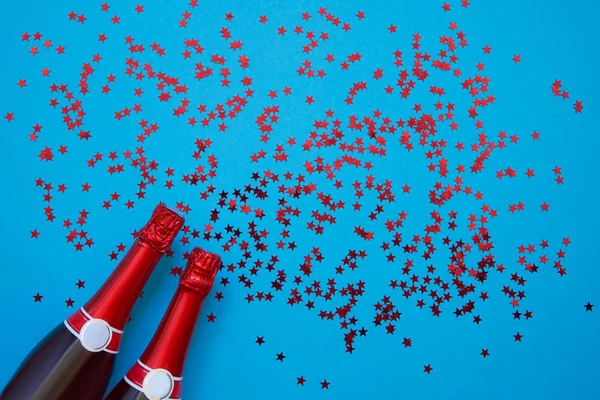 Botellas de champán con estrellas de confeti sobre fondo azul claro . — Foto de Stock