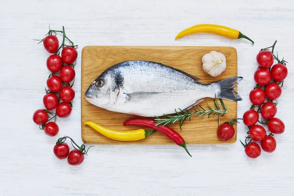 Peixe dorada cru com legumes em tábua de corte de madeira. Conceito de alimentação saudável. Vista superior, espaço de cópia . — Fotografia de Stock