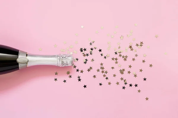 Botella de champán con estrellas de confeti sobre fondo rosa. Copia s — Foto de Stock