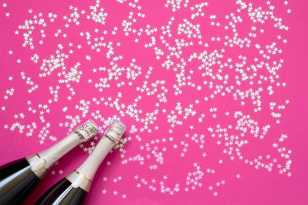 Parlak pembe arka plan üzerinde hologrphic konfeti yıldız ile şampanya şişesi. Kopya alanı, üst görünüm — Stok fotoğraf