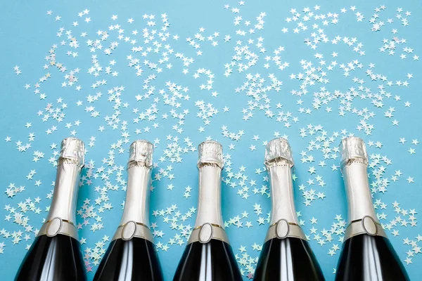Cinci sticle de șampanie cu stele confetti holografice pe lumină — Fotografie, imagine de stoc