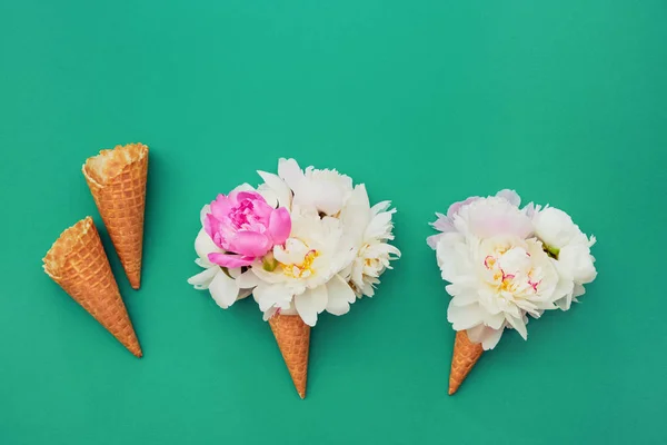 Cônes de crème glacée gaufre avec des fleurs pivoines blanches sur fond vert — Photo