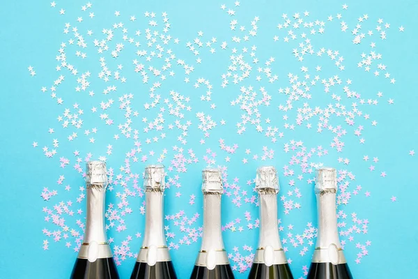 Cinco garrafas de champanhe com estrelas de confete holográficas em brilhante — Fotografia de Stock