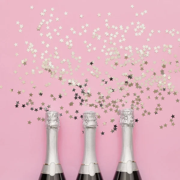Três garrafas de champanhe com estrelas de prata confetti em pino brilhante — Fotografia de Stock