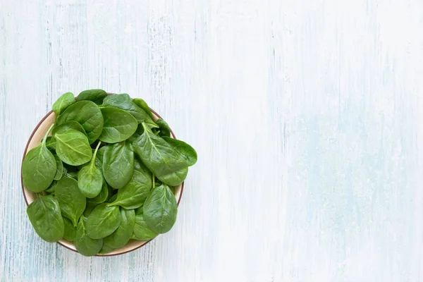 Fresh spinach leaves on white plate. Healthy vegan food. Top vie — Stock Photo, Image