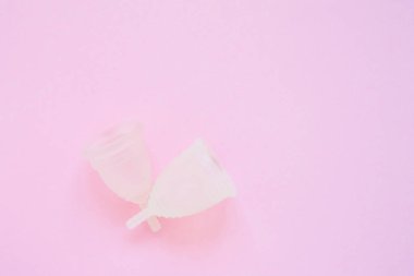 Pembe arka planda iki menstrüel fincan. Dönemde alternatif kadınsı hijyen ürünü. Kadın sağlığı konsepti. Boşluk Kopyala