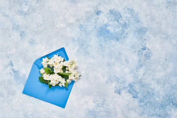 Philadelphus oder orangefarbene Blüten in blauem Umschlag auf blauem Hintergrund. Geburtstag, Muttertag, Konzept. Kopierraum, Ansicht von oben. — Stockfoto