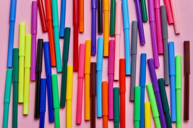 Pembe zemin üzerinde renkli keçeli kalem. Okul konseptine geri dönelim. Üst te. Renkli arka plan.