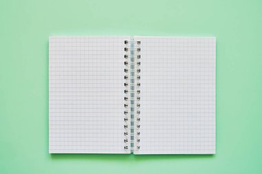 Boş sayfalı açık not defterinin üst görünümü, yeşil arka plan daki okul not defteri, spiral not defteri.