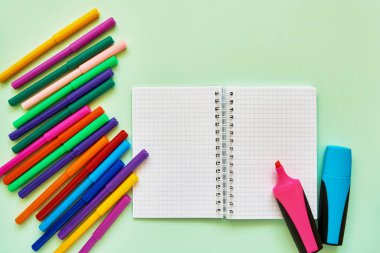 Yeşil arka planda okul konuları. Keçeli kalem ve yeşil zemin üzerinde not defteri. Okul konseptine geri dönelim. Düz döşeme, kopyalama alanı. 