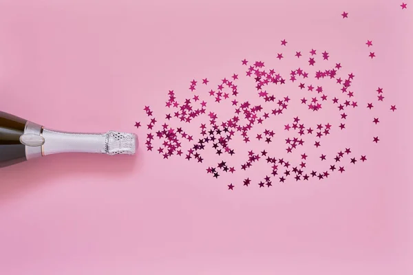 Botella de champán con estrellas de confeti rosa sobre fondo rosa claro. Piso laico de Navidad, aniversario, despedida de soltera, concepto de celebración de Año Nuevo. Copiar espacio, vista superior . — Foto de Stock