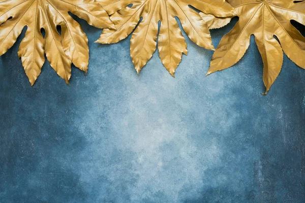 Goldene tropische Blätter vor blauem Hintergrund. Minimales sommerliches exotisches Konzept mit Kopierraum. Kopierraum, Ansicht von oben — Stockfoto
