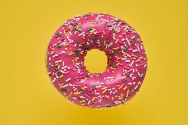 Serpiştirilmiş Pembe Donut. Sarı arka plan üzerine sırlı serpiştirilmiş çörek. Üst görünüm, kopyalama alanı.