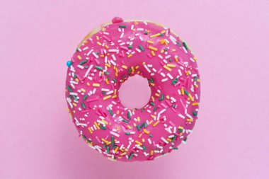 Serpiştirilmiş Pembe Donut. Pembe arka plan üzerine sırlı serpiştirilmiş çörek. Üst görünüm, kopyalama alanı.