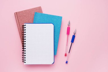 Pastel pembe zeminde tasarımınız için maket olarak kalemlerile spiral not defteri. Okul konseptine geri dönelim. Kopya alanı, üst görünüm.